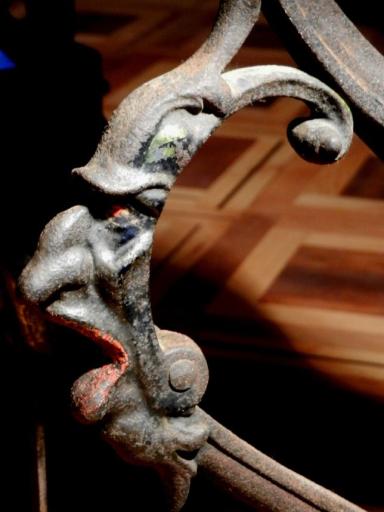 Nahaufnahme eines verzierten, antiken Metallgestells mit Fratze
